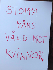 Plakat med texten 'Stoppa mäns våld mot kvinnor'.